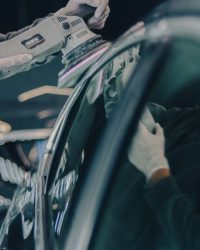 Close-up of car detailing process with polishing machine and reflective surface in workshop.
