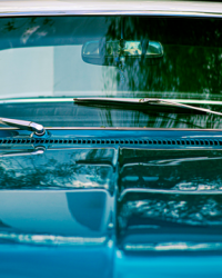 A close-up view of a classic blue vintage car windshield with reflections.