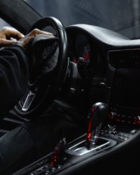 Close-up of a person cleaning a car's dashboard and steering wheel, focused on interior maintenance.