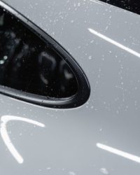A detailed view of a white car with water droplets after a wash, showcasing its shine.