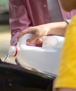 Close-up of hands pouring water into a car engine, focusing on auto maintenance.